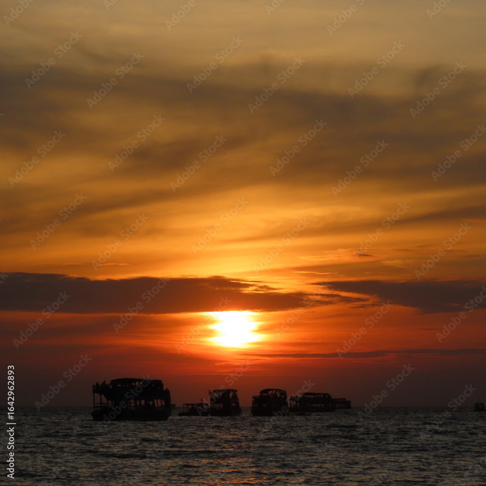 Fototapeta premium bright red sunset with shadows of boats in the water