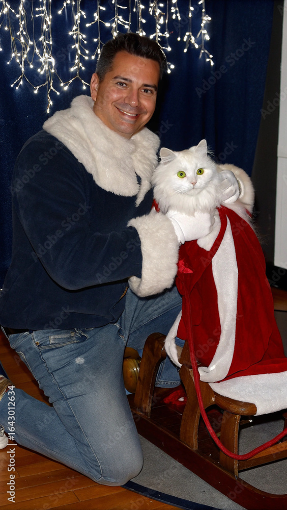 Obraz premium A close-up shot of Ded Moroz kneeling beside a fluffy white cat wrapped in a cozy red scarf. The cat sits on a wooden sleigh filled with wrapped gifts, its green eyes gleaming with curiosity. Ded Moro
