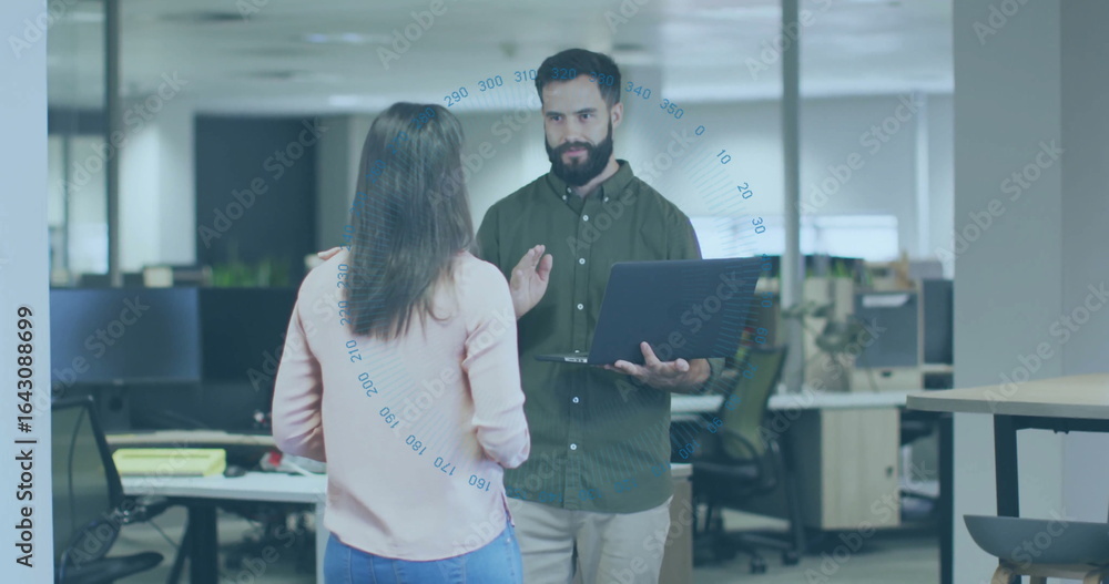 Obraz premium Holding laptop, coworkers wearing business attire discussing project in open plan office