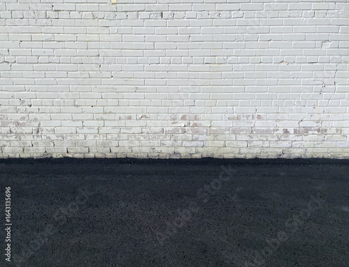Old brick white wall and asphalt floor