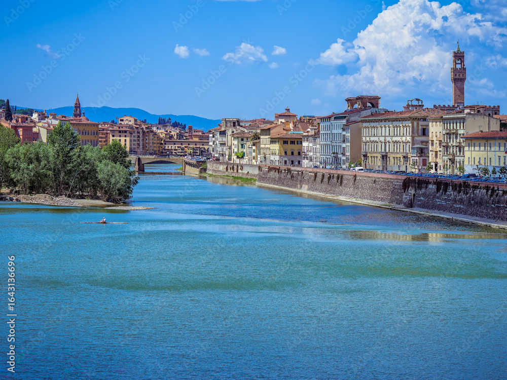 Fototapeta premium Lungarno della Zecca runs alongside the Arno, with the belfry of Santa Maria della Croce standing gracefully in the background, adding a touch of historic elegance to the Florentine riverside.
