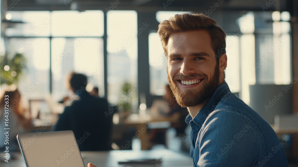 Obraz premium Smiling Young Professional Working on Laptop in a Cozy Cafe