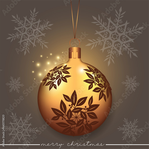 A beautiful golden ornament adorned with an elaborate leaf-floral design on a backdrop with scattered snowflakes.
