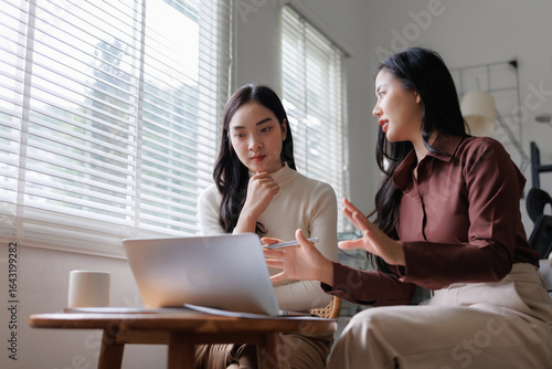 Businesswomen discussing work using laptop in office