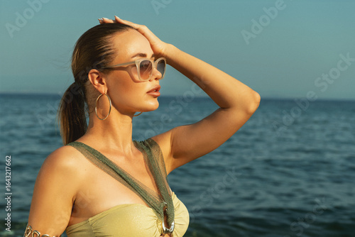 Bilde på lerret Attractive blue-eyed blonde wearing khaki bikini and sunglasses posing beachside
