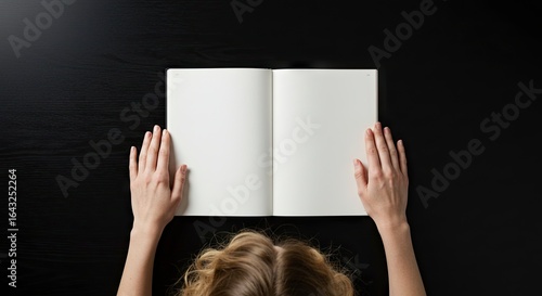 Open blank book with hands topdown view Dark textured surface part of a person with blonde hair