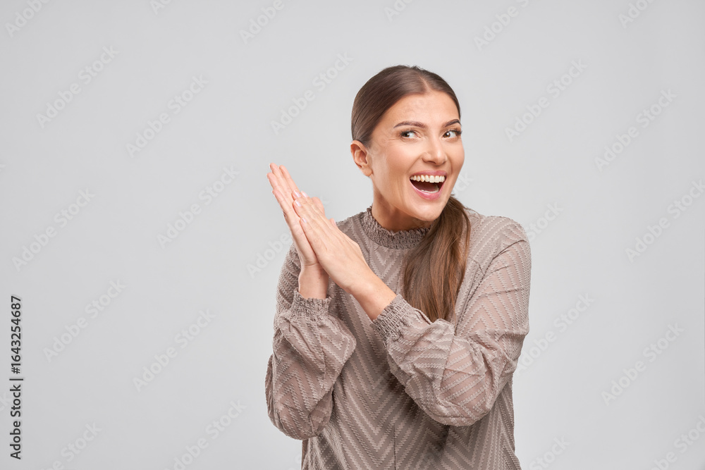 Excited woman clapping hands in studio portrait