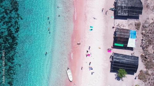 Aerial drone view of Pink Beach with turquoise water, in Indonesia, with tourists relaxing. Komodo National Park
