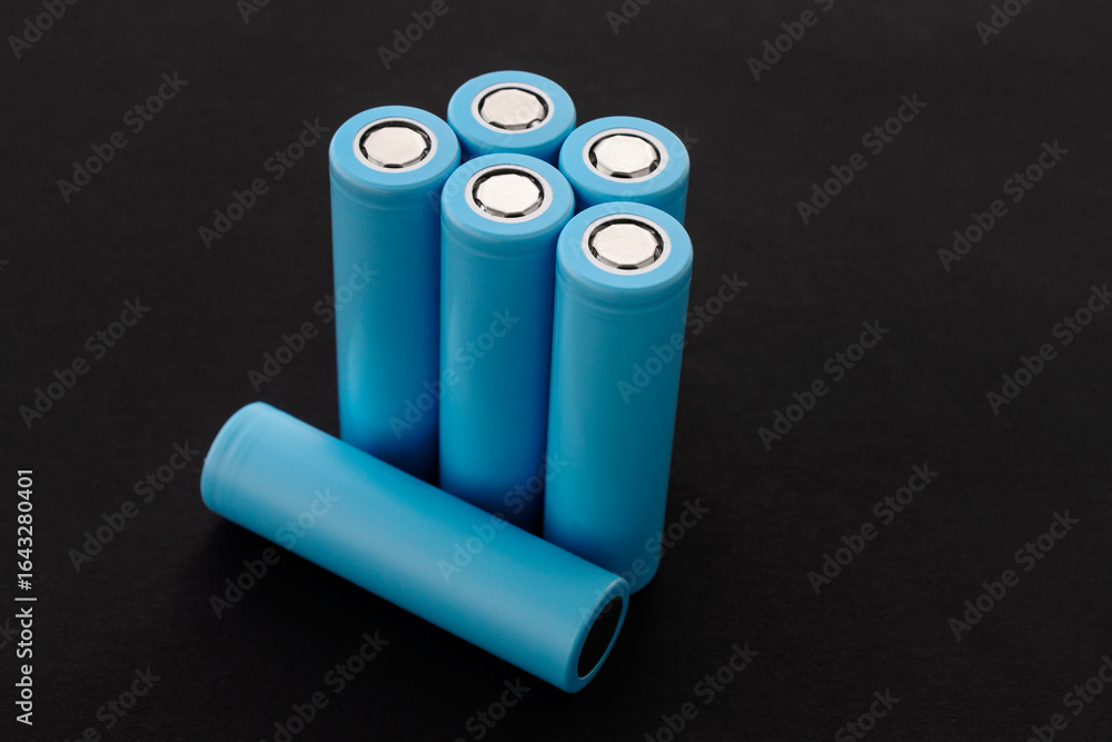 Stack of 18650 cylindrical batteries on black background, rechargeable lithium-ion batteries for electrical appliances and devices. Battery cell or secondary element. With copy space. Stack of 18650 cylindrical batteries on black background, rechargeable lithium-ion batteries for electrical appliances and devices. Battery cell or secondary element. With copy space.