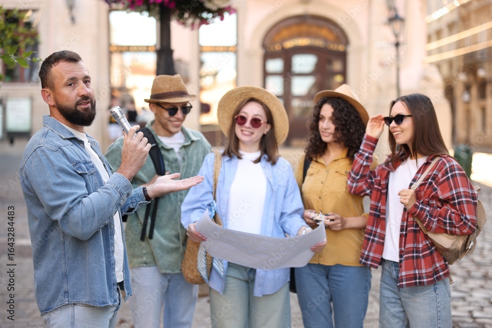 Guide with microphone and group of tourists on city street during excursion Guide with microphone and group of tourists on city street during excursion