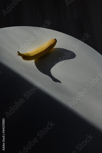 Fotografía A sunlit kitchen moment: banana placed on the table. Dark shadow
