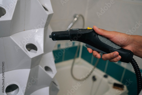 Wallpaper Mural Detail cropped shot of unrecognizable male using steam cleaner to sanitize vertical hydroponic tower garden in bathroom, demonstrating modern approach to indoor gardening. Concept of home gardening. Torontodigital.ca