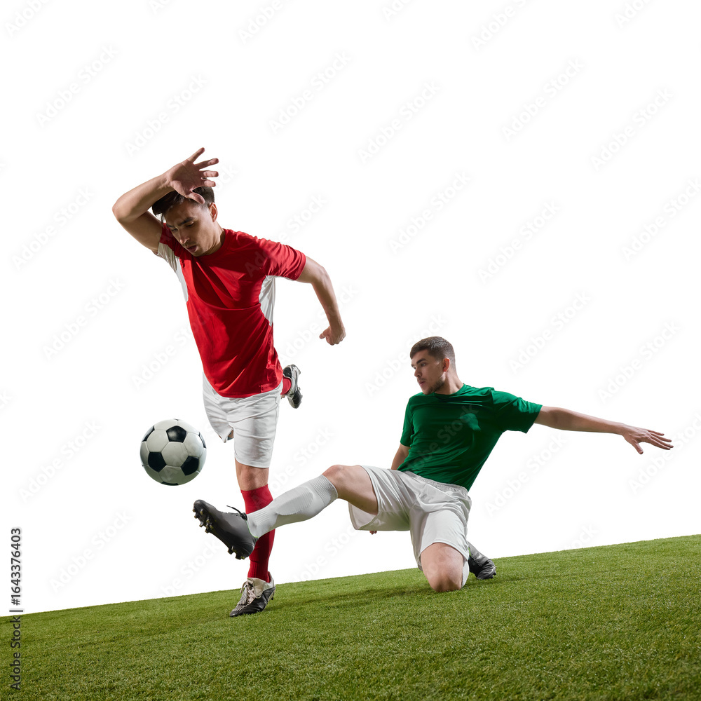 Obraz premium Football player in green jersey performing slide tackle against opponent in red jersey during match on grass. Concept of sports rivalry, physical skill, and competitive spirit.