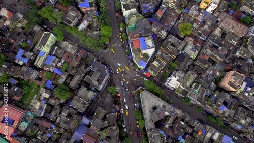  A top angle shot of cars, cabs and bikes moving on a busy street or crossroad junction in a congested part of the downtown Kolkata or Calcutta city, India surrounded by the century old buildings. 