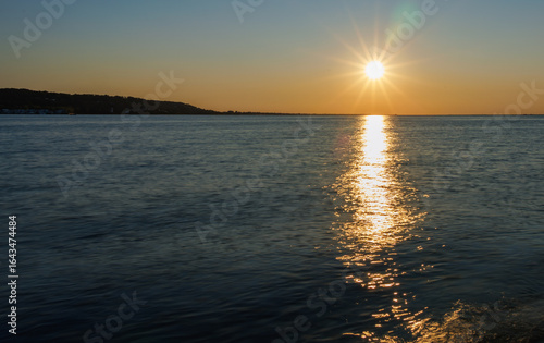 Golden sunset over calm ocean waters, with warm reflections stretching to the horizon, serene coastal landscape, tranquil sky, and peaceful seascape perfect for travel and nature themes.