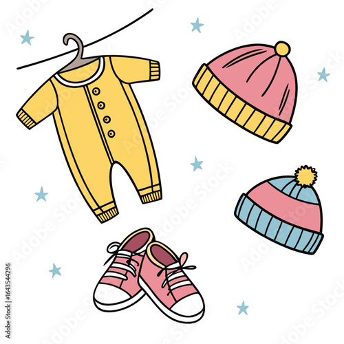 Cute cartoon baby clothes including a yellow onesie hanging on a hanger two colorful knitted hats and pink sneakers scattered with light blue stars on a white background