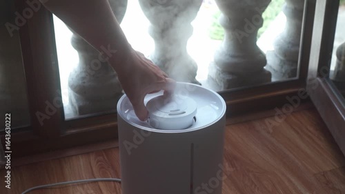 Hand adjusts direction of humidifier mist on a dry summer's day