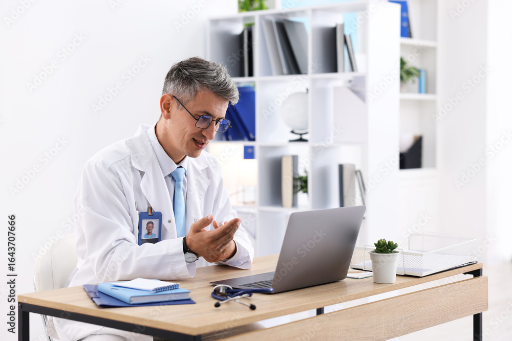 Fototapeta premium Telemedicine. Doctor having video call with patient via laptop indoors