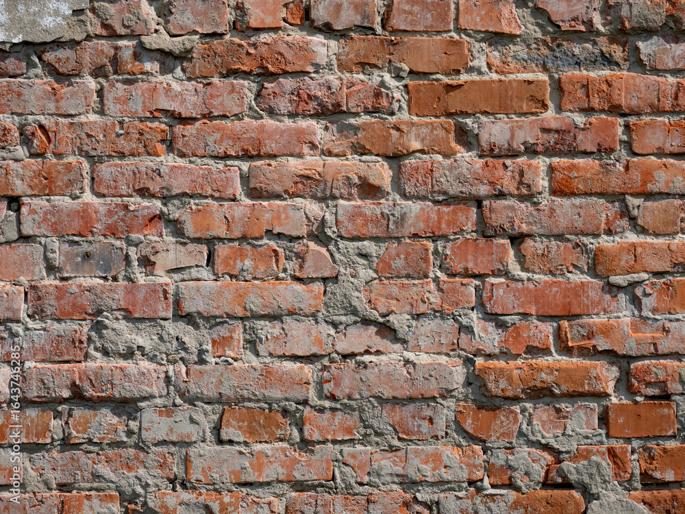 Fototapeta premium The texture of a very old vintage brick wall with residual elements of plaster decoration.
