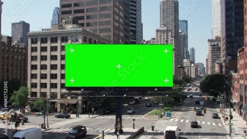 Green screen billboard on city street.