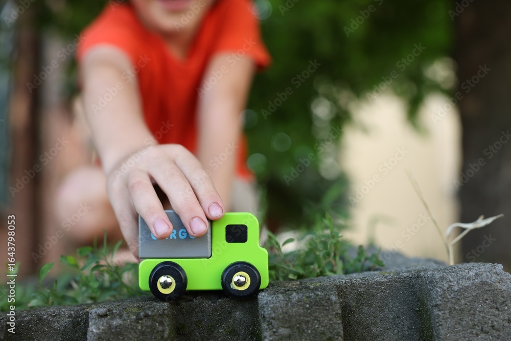Fototapeta premium Little boy playing with toy car outdoors, closeup. Space for text