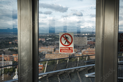 Panoramic city view from high-rise building with warning sign in foreground during overcast afternoon