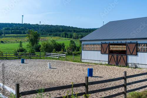 A horse training facility with wind turbines in the background