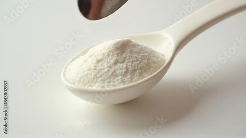 Powdered supplement in a ceramic spoon against a pure white background ready to use