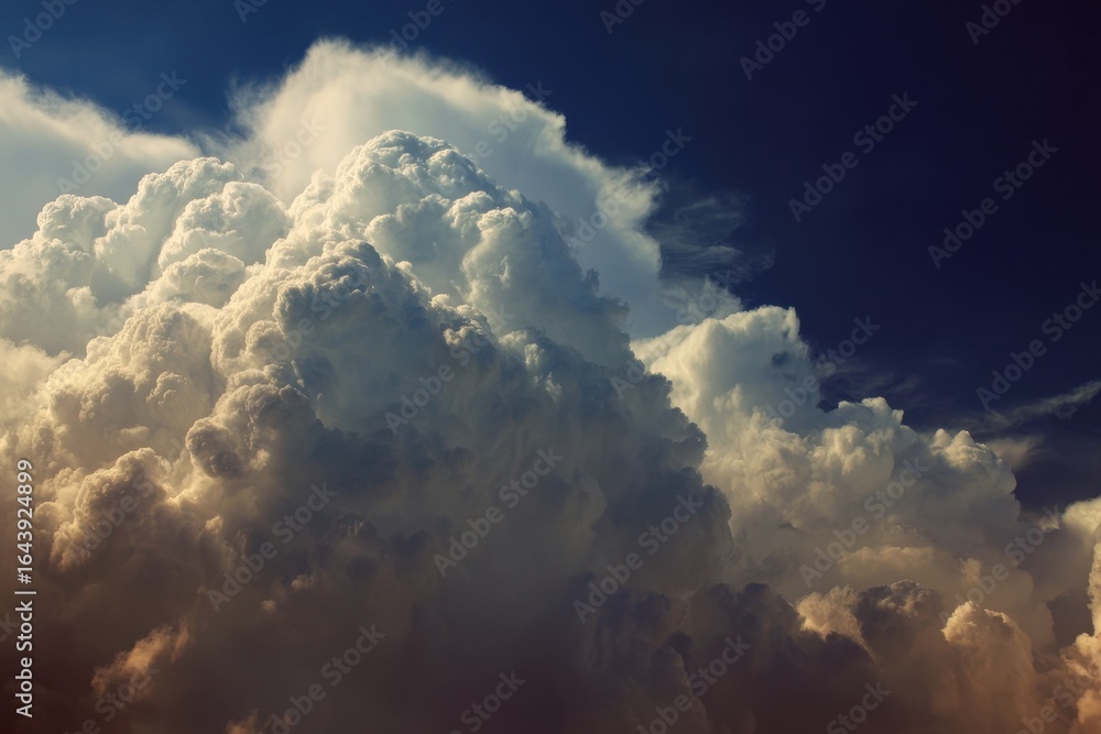 Naklejka premium Majestic clouds billow in the sky creating a dramatic atmosphere during sunset over a serene landscape