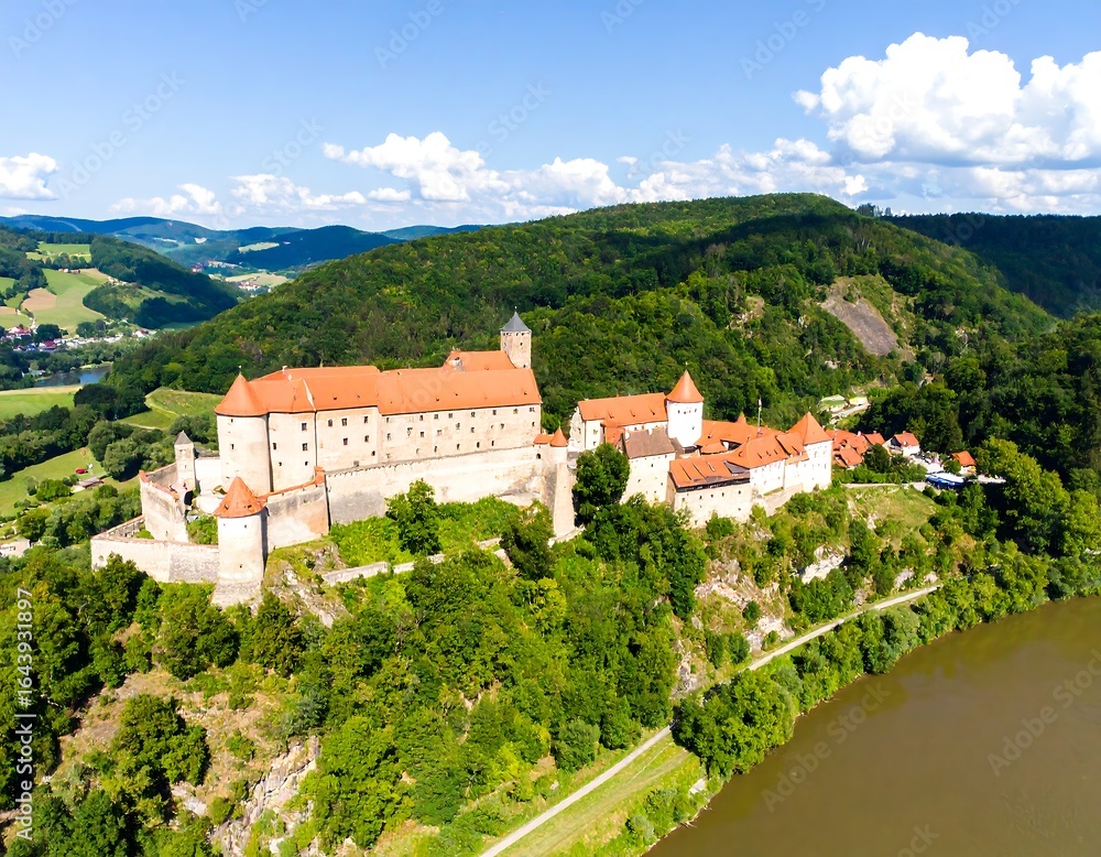 Obraz premium Aerial view of a medieval castle nestled on a hillside overlooking a valley and river