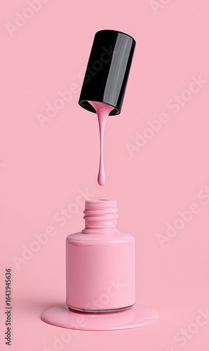 Pink nail polish bottle with cap raised, showing polish dripping back into bottle against a pink background