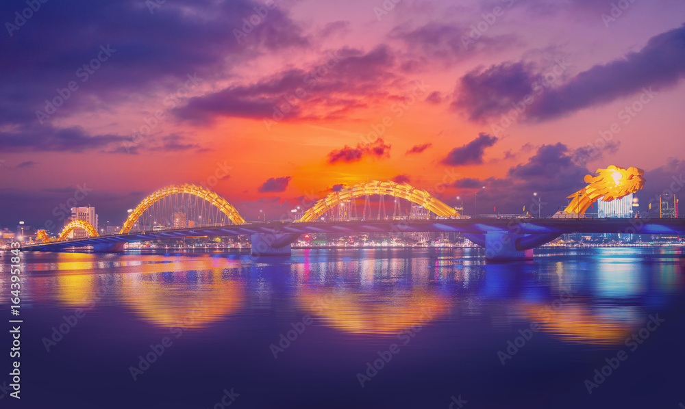 Naklejka premium Dragon bridge at night in Da Nang Vietnam, illuminated architecture and scenic reflections