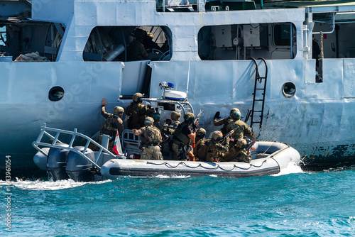 Military soldiers boarding ship for control and search for refugees on ship deck during operation on sea.