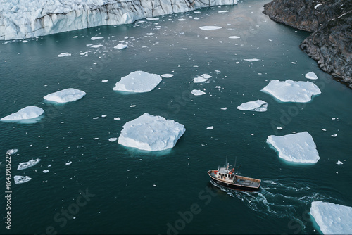 Aerial view of a boat by a bay with icebergs and a glacier