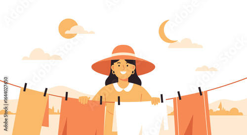 Cheerful woman in wide brim hat hanging laundry on clothesline in scenic outdoors