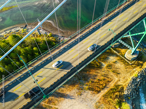 aerial view of Lions Gate Bridge in Vancouver, Canada during sunset with a blue sky, ocean, and mountains at distance