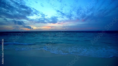 Beautiful sunset over the sea with waves crashing on the beach at twilight