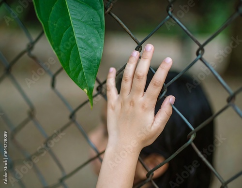 Child's hand touches metal fence
