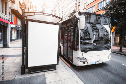 Vertical city street billboard mockup with blank white space for advertising, positioned on sidewalk near parked cars and decorative trees in an urban environment