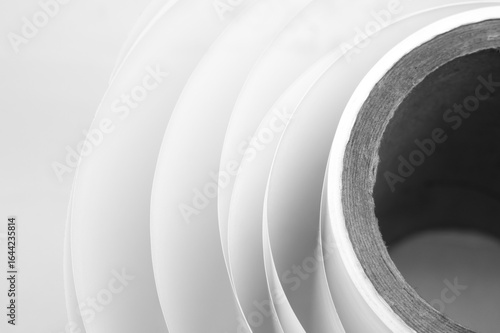 White polygraph paper on a cardboard core. A bundle of leftover paper in a printing house. Material for the printing industry. Selective focus