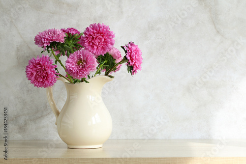Wallpaper Mural Pink aster flowers in white jug standing on wooden table Torontodigital.ca