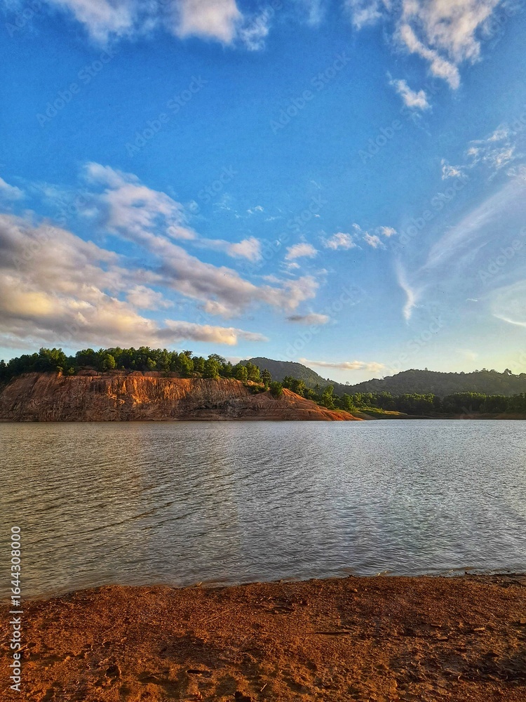 Obraz premium Scenic Lake Shore with Blue Sky and Clouds