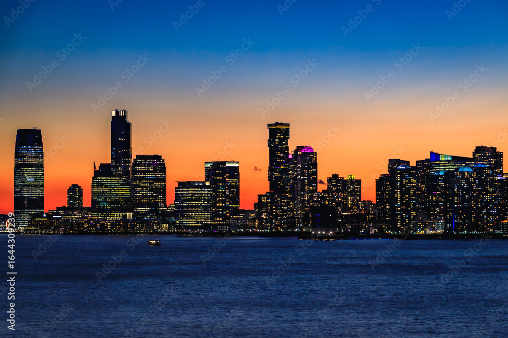 Obraz premium Jersey City skyline silhouette from New York, dramatic sunset over Hudson River