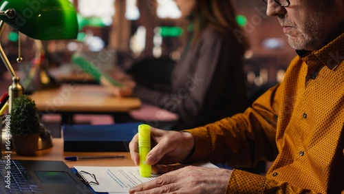 Fotografie Elderly student using highlighter pen to memorize lesson papers, applying a study strategy with essential information from courses