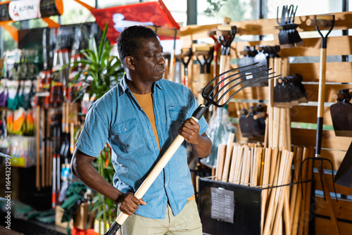 Wallpaper Mural Portrait of african american man choosing pitchfork in gardening market Torontodigital.ca