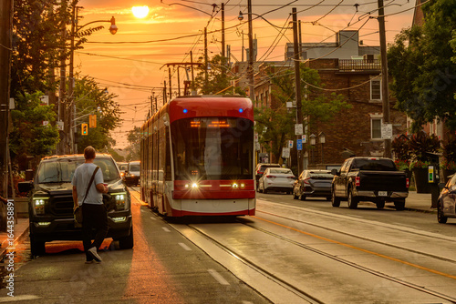 public transport: modern tram car on city street shot in the toronto beaches early on a hot  summer morning red tram