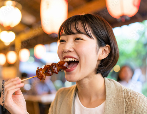 焼き鳥を食べる若い女性/Young woman eating yakitori