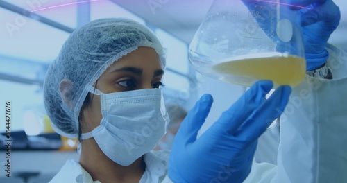 Photography Inspecting lab technician wearing hairnet, mask, lab coat and gloves in lab, wit