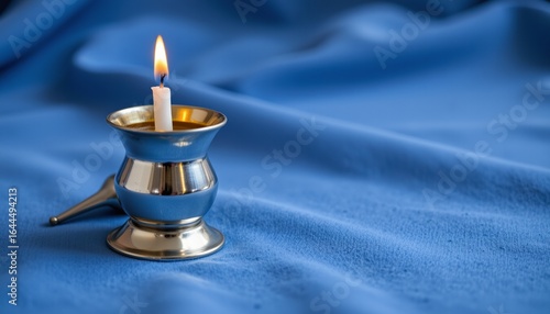 silver candle snuffer on blue cloth, hanukkah, no people, no text, no logo