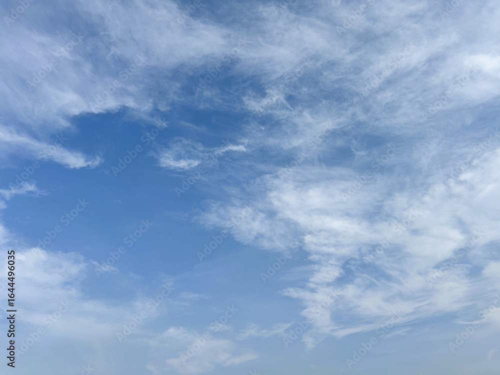 Fototapeta premium Blue sky with wispy cirrus clouds and a clear patch, perfect for a peaceful natural background